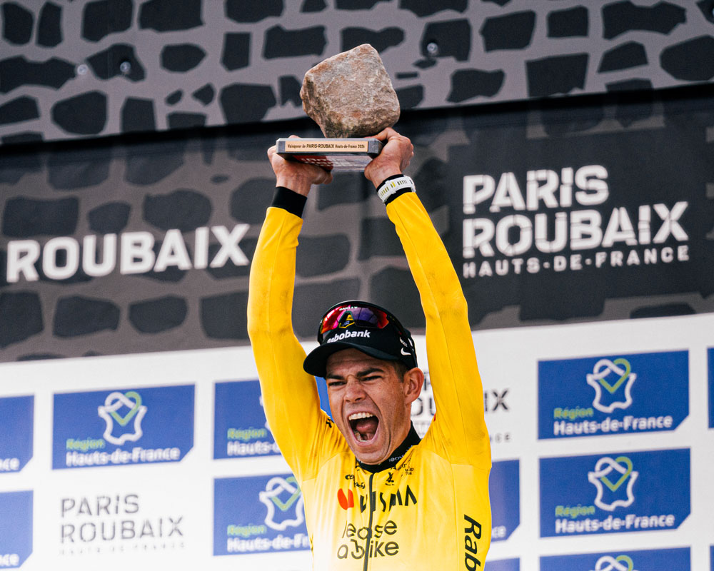 Wout Van Aert celebrates his Paris–Roubaix 2026 victory on the podium holding the cobblestone trophy